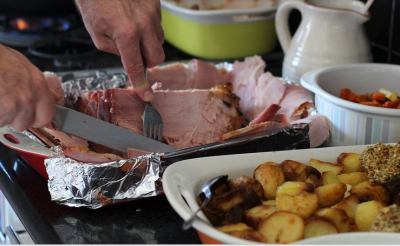 ham being carved with potatoes beside